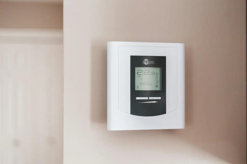 A white and grey heating thermostat set to nineteen and a half degrees