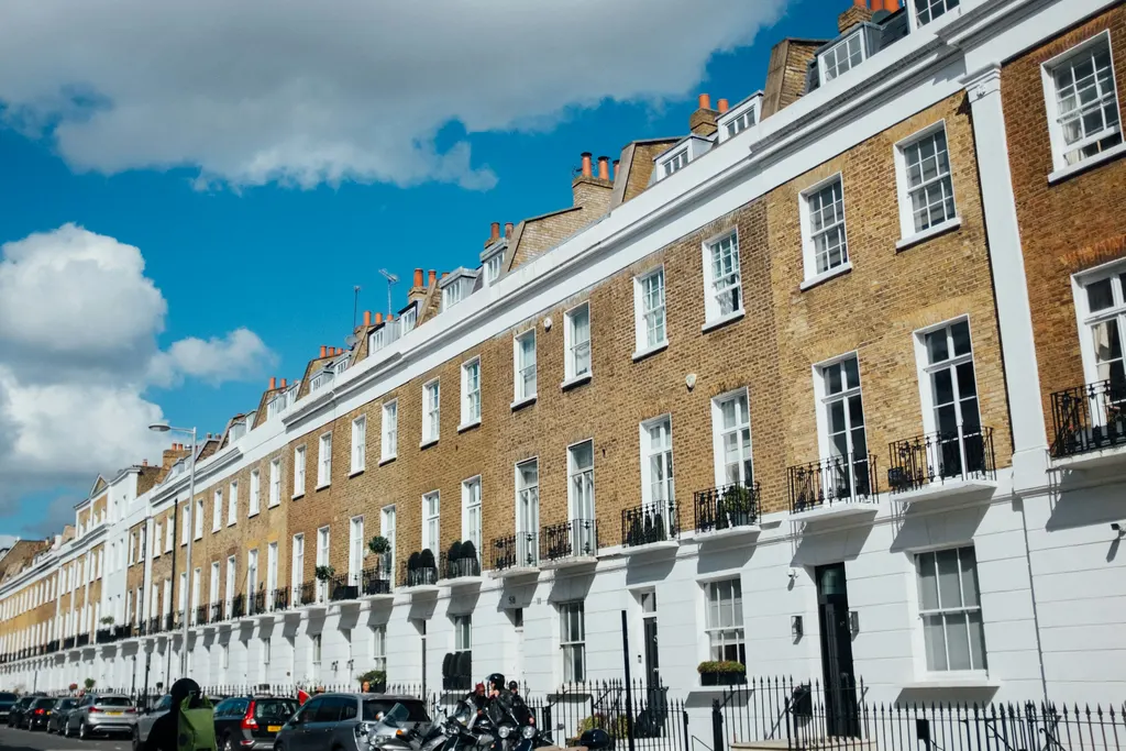A row of traditional brick terraced houses under a blue sky