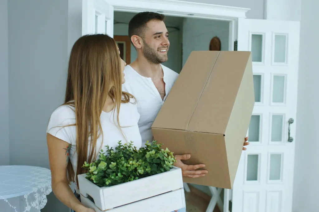 A couple carrying cardboard boxes into their new home