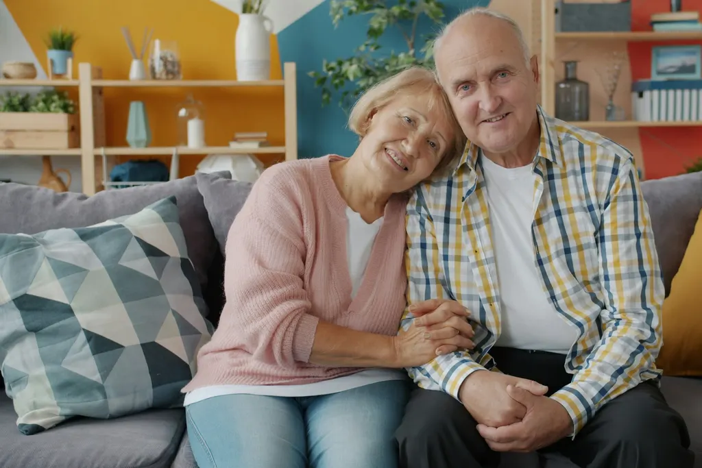 A couple sitting together on their sofa at home, relaxed and smiling
